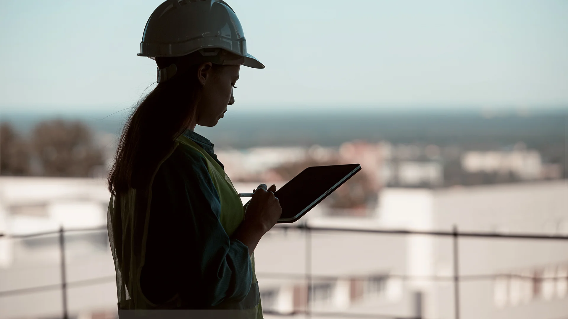 Construction professional in hard hat holding handheld device