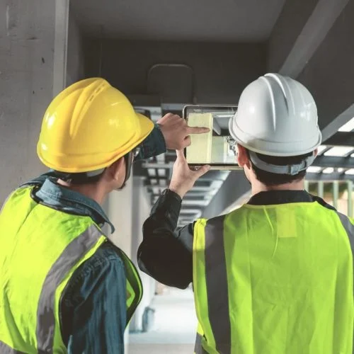 Two construction professionals on-site with handheld device