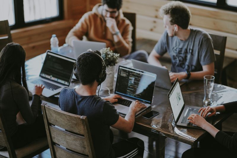 Group of people working around laptops